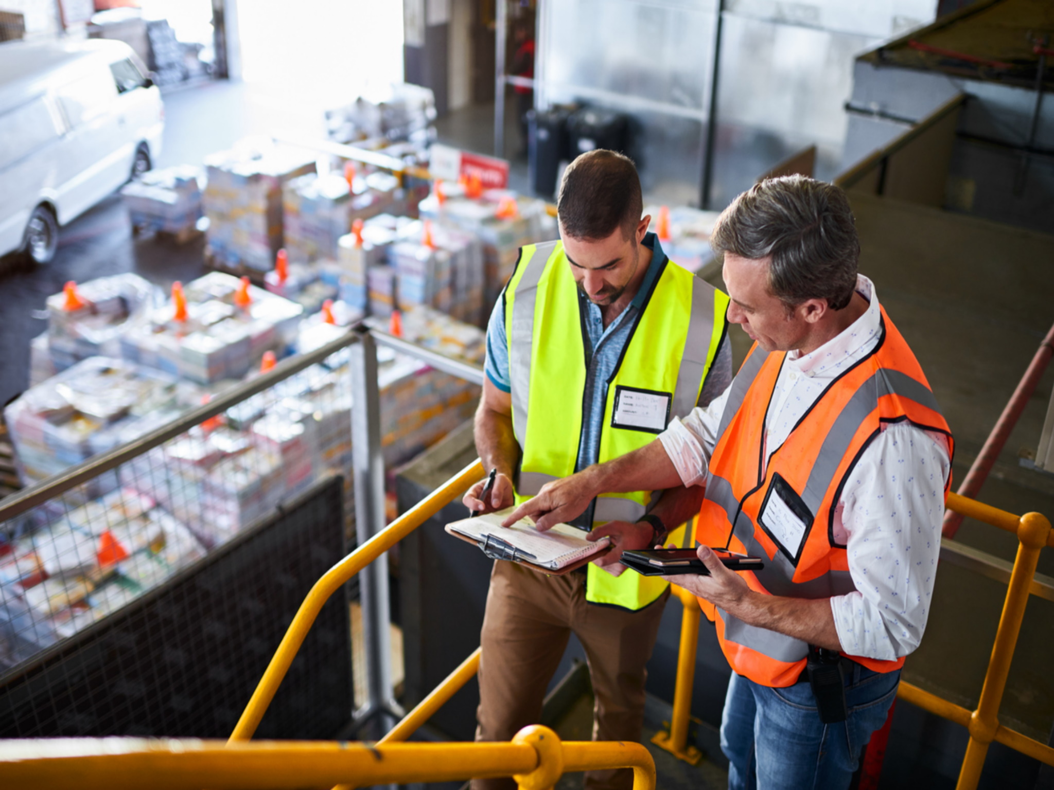 2 manufacturing professionals with clipboards discussing logistics coordination