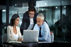 3 professionals working on laptop for disaster recovery