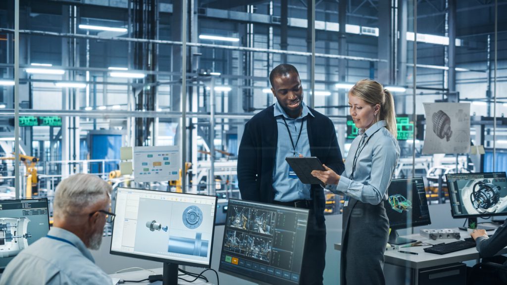 Two employees work on a laptop to overcome disruptions in manufacturing
